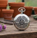 Silver pocket watch with Celtic knot design on a white background